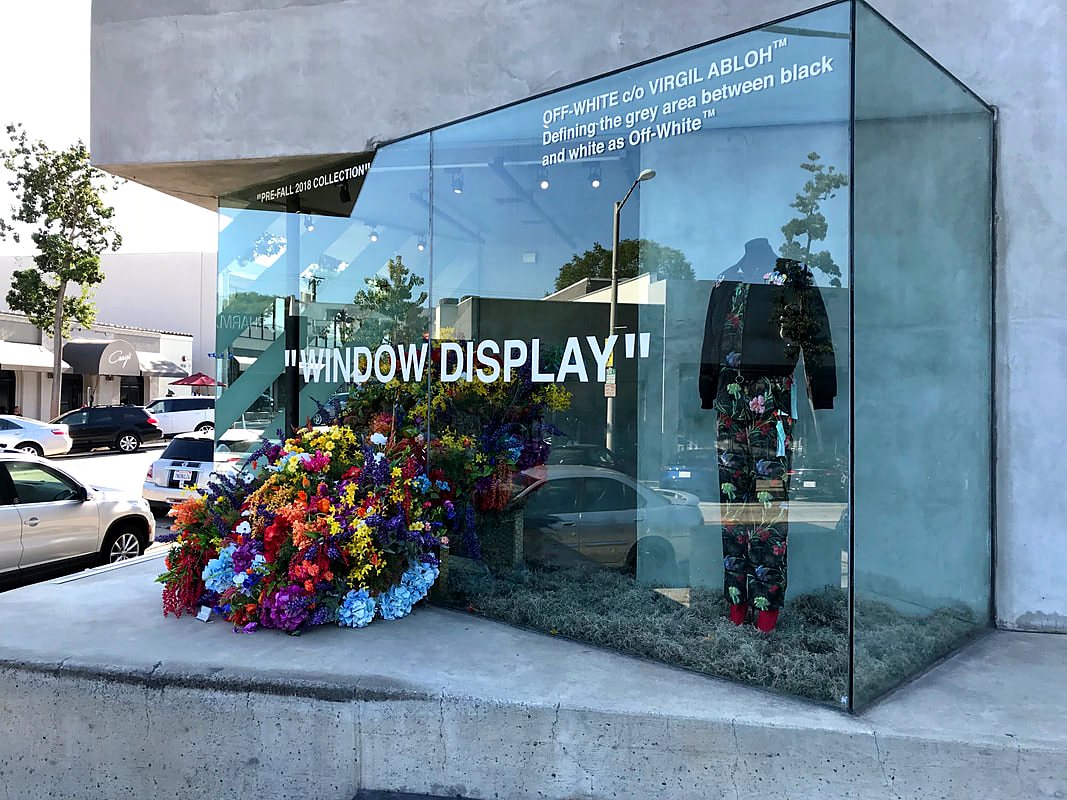 Artificial flower window display installed in a glass boutique storefront