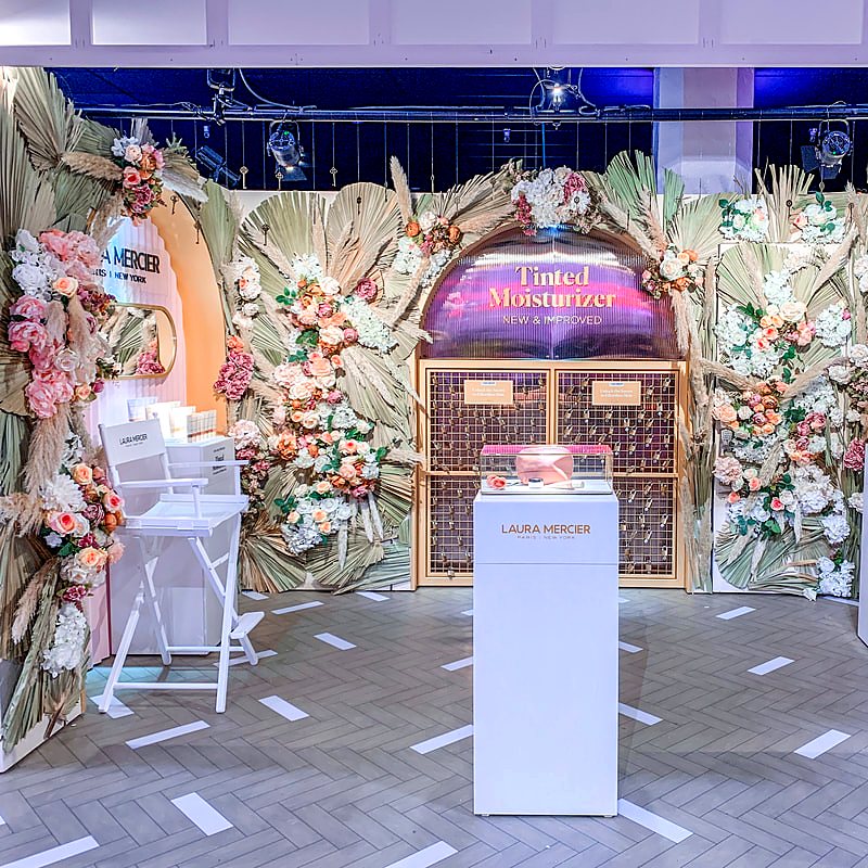 Dried palm fronds, pampas and pink and white blooms framing a beauty brand pop-up