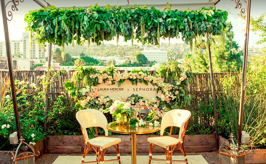 Hanging greenery canopy over a floral wreath brand backdrop with a bistro table