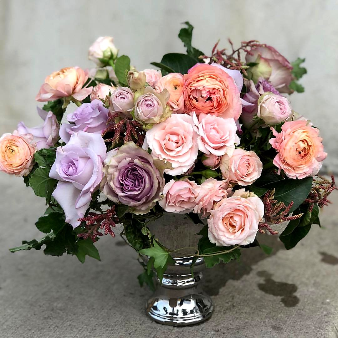 Pastel roses and peach ranunculus in a silver urn