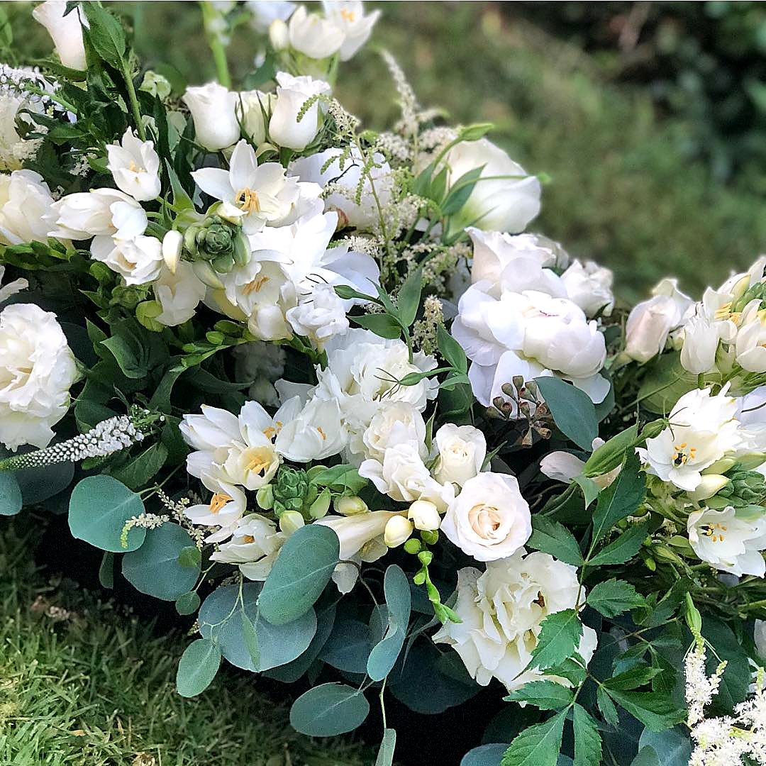 Low arrangement of white roses, lisianthus and eucalyptus on grass